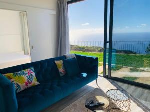 a blue couch in a living room with a view of the ocean at northsouthviescasinha in Calheta