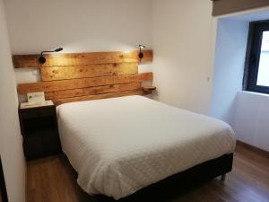 - une chambre avec un lit blanc et une tête de lit en bois dans l'établissement Sambuc'asa - Serra da Estrela, à Sabugueiro