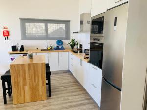 a kitchen with white cabinets and a wooden table at northsouthviescasinha in Calheta