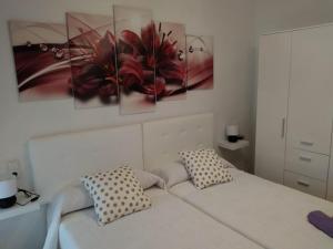 ein Schlafzimmer mit einem Bett mit drei Gemälden an der Wand in der Unterkunft CASA DANIELA Apartamentos in Estella