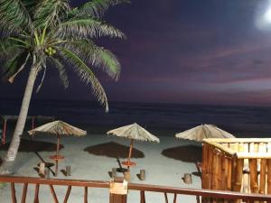 una spiaggia con ombrelloni e l'oceano di notte di Bungalows La Perla Playa Azul a Playa Azul