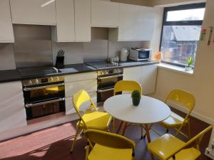 a kitchen with a white table and yellow chairs at Modern City Home with 5 Ensuites and Private Parking! Perfect for Working teams in Norwich