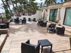eine Terrasse mit Stühlen, Tischen und Sonnenschirmen in der Unterkunft Bungalows La Perla Playa Azul in Playa Azul