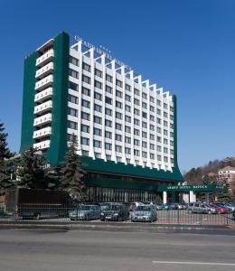 a large building with cars parked in a parking lot at Grand Hotel Napoca in Cluj-Napoca