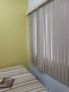1 dormitorio con 1 cama y ventana con persianas en Casa 4 pessoas 100m do mar 013, en Florianópolis