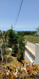 un jardín con flores y una valla y el océano en Casa 4 pessoas 100m do mar 013, en Florianópolis