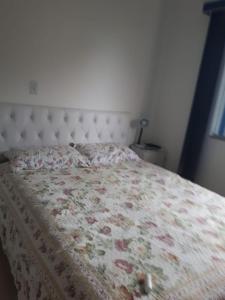1 dormitorio con 1 cama con colcha de flores en Casa 4 pessoas 100m do mar 013, en Florianópolis
