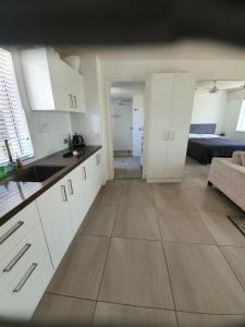 a kitchen with white cabinets and a living room at Mooloolaba Beach Beachwalk in Mooloolaba