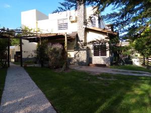 Una gran casa blanca con un patio de césped. en DUPLEX AL SUR, en Villa Gesell