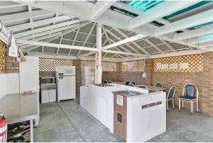 a kitchen with white appliances and chairs in a room at Discovery Parks - Swan Valley in Caversham