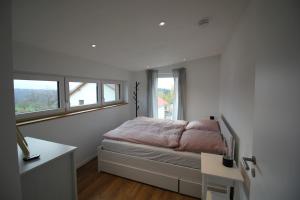 a bedroom with a bed and a desk and windows at Modernes Ferienhaus im Schwarzwald in Freiamt