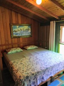 1 dormitorio con 1 cama en una pared de madera en Casa da Floresta en Guarda do Embaú