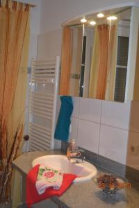 ein Waschbecken mit einem roten Handtuch und einem Spiegel in der Unterkunft Lee1 in Graal-Müritz