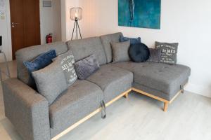 a gray couch in a living room with pillows on it at Modern appartement met uniek zeezicht in Koksijde