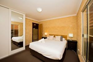 a bedroom with a large white bed and a bathroom at Discovery Parks - Bunbury Foreshore in Bunbury