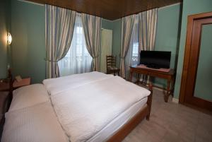 a bedroom with a bed and a desk with a computer at Hôtel - Restaurant Le Manoir in Vaulruz