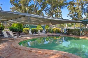 a swimming pool with a large umbrella over it at Discovery Parks - Clare in Clare
