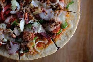 a pizza with meat and vegetables on a table at Pollos Hotel & Gallery in Rembang