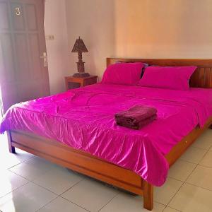a large bed with a pink blanket on it at Karimunjannah House in Karimunjawa