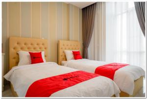 two beds with red pillows in a room at RedDoorz Plus @ Madukoro Raya Semarang in Kalibanteng-lor