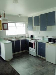 una cocina con armarios azules y electrodomésticos blancos en Fantastic Two Bedroom Unit en Whakatane