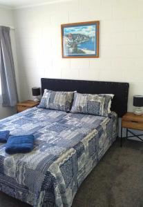 a bedroom with a bed with a blue comforter at Fantastic Two Bedroom Unit in Whakatane