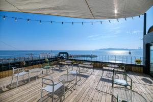 einen Balkon mit Stühlen, Tischen und Meerblick in der Unterkunft Mipo Oceanside Hotel in Busan