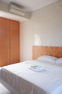 a bedroom with a large white bed with a wooden cabinet at Pemondokan Pratama in Nusa Dua