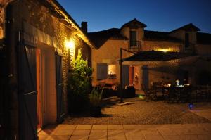 un patio al aire libre por la noche con una mesa y una sombrilla en Chambres d'Hôtes La Grange Au Bois, en Champagne-et-Fontaine