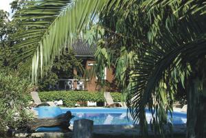 a swimming pool with a palm tree in front of a house at Navarro Hill Resort in Porto Santo Stefano