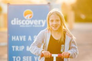 德文港Discovery Parks - Devonport的一名年轻女孩在标志前骑摩托车