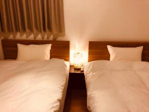 a bedroom with two beds and a night stand with a clock at L's Mt.Fuji vacation rental in Fujikawaguchiko