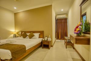a hotel room with a bed and a dresser with flowers on it at Hotel Pearl Palace in Cochin