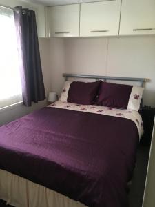 Un dormitorio con una cama con sábanas moradas y una ventana en Marshlands Lakeside Nature Retreat, en Barton-upon-Humber