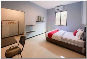 a bedroom with a bed and a chair in it at RedDoorz Syariah near T2 Juanda Airport 2 in Dares