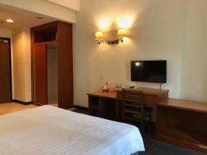 a hotel room with a bed and a desk with a television at Garden View Hotel in Bahau