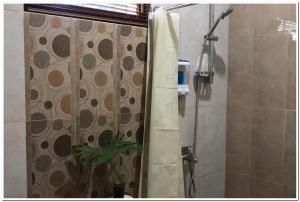 a shower with a shower curtain with a plant in it at RedDoorz Syariah at Omah Sawah in Balong