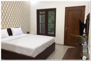 a bedroom with a bed and a window and a television at RedDoorz Syariah at Omah Sawah in Balong