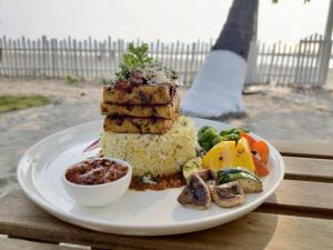 a plate of food with rice and vegetables on a table at Buena Vida Beach Resort in Morjim