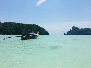 a boat sitting in the water near a island at The Mantra Hotel Kata Noi in Kata Beach