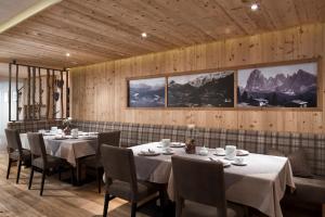 a dining room with tables and chairs and mountains at Hotel Comploj Adults only in Selva di Val Gardena