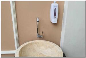 La salle de bains est pourvue de toilettes et d'un distributeur de savon sur le mur. dans l'établissement RedDoorz near Moro Mall Purwokerto 2, à Purwokerto