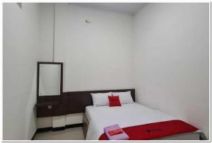 1 dormitorio con cama con espejo y manta roja en RedDoorz near Moro Mall Purwokerto 2, en Purwokerto