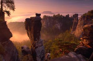 eine Person, die auf einem Felsen in den Bergen steht in der Unterkunft Berghotel Bastei in Lohmen