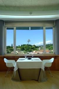 a table and chairs in a room with a large window at Colón Tuy in Tui