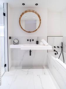 Baño blanco con lavabo y espejo en Maison Bellevue en Saint-Tropez
