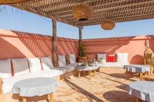 a patio with white couches and tables in a room at Riad Tchaikana in Marrakech