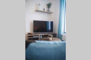 een woonkamer met een blauwe bank en een tv bij Green Suite & Spa in Bergen