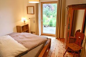 a bedroom with a bed and a window and a chair at Ferienwohnungen Mittermayer in Aschau im Chiemgau