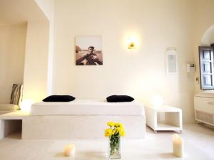 a white bedroom with a bed and a vase of flowers at Alafouzou Cave Loft by SV in Oia